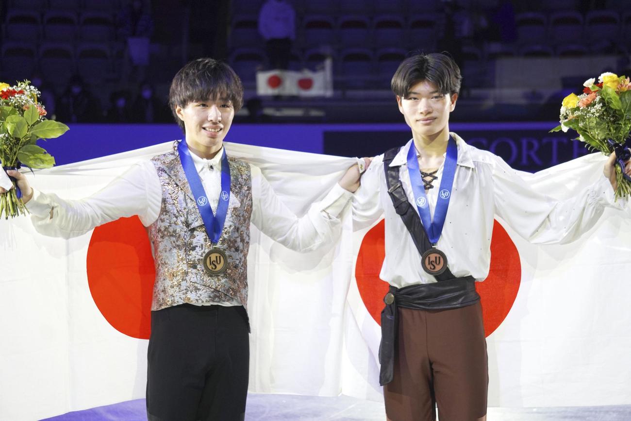 日の丸を広げる、男子で優勝した三浦（左）と3位の吉岡（共同）