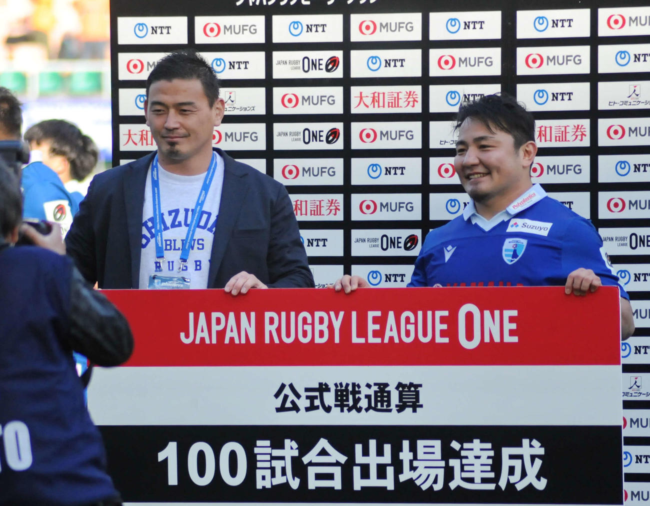 静岡ブルーレヴズの日野（右）はリーグ戦100試合出場を達成し、祝福した五郎丸CROと記念撮影に応じる