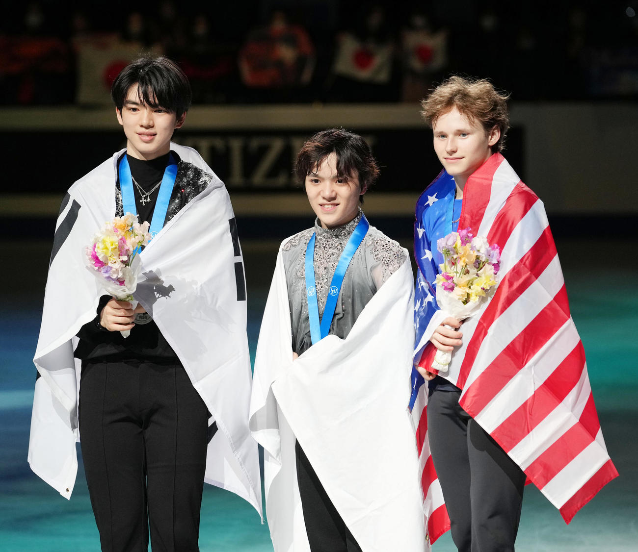 国旗を背に笑顔を見せる宇野。左は2位のチャ・ジュンファン、右は3位のイリア・マリニン（撮影・横山健太）