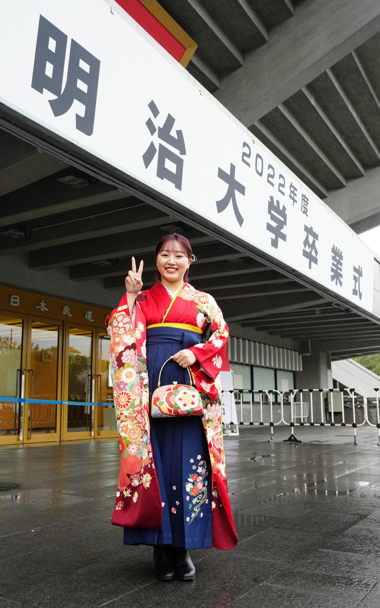 明大卒業式に臨み、看板の前で写真に納まるフィギュアスケートの樋口（撮影・江口和貴）