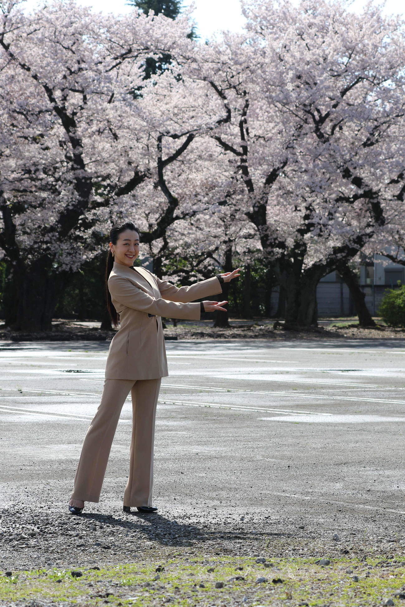 桜が満開の建設予定地に立つ浅田さん