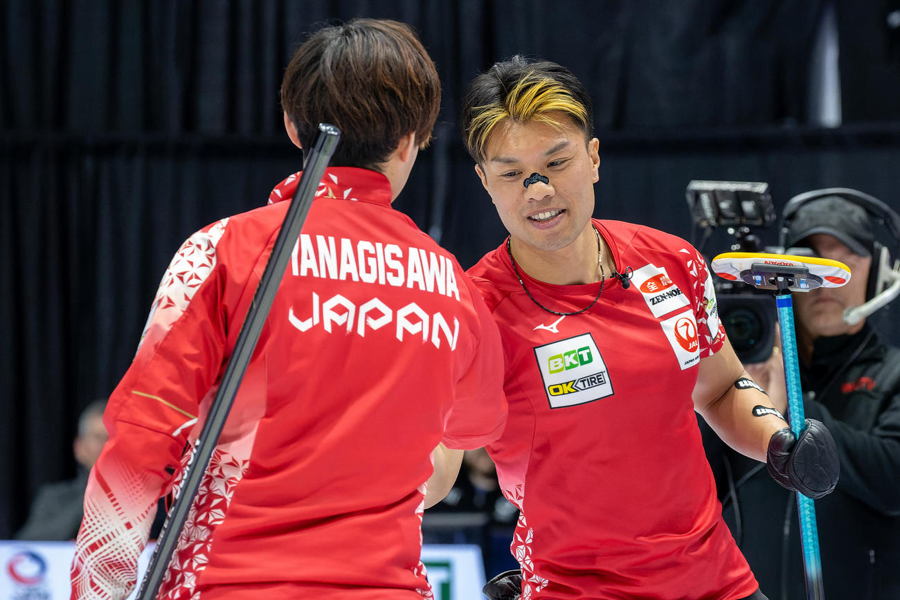 世界選手権1次リーグ米国戦で握手を交わすカーリング男子日本代表の柳沢（手前）と山口（奥）（C）WCF／Steve Seixeiro