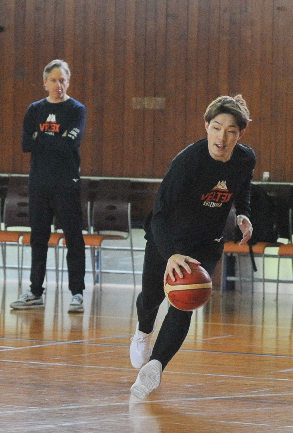 ドリブルするベルテックス静岡PG岡田（右）。後方左はファクンド・ミュラー監督　