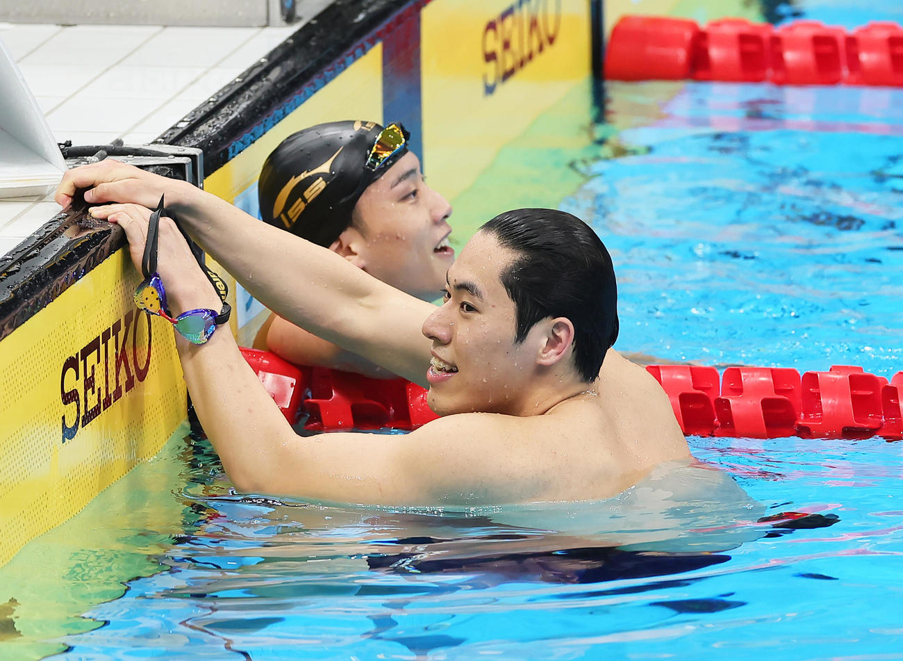 男子200メートルバタフライ決勝を終え、健闘をたたえ合う優勝の本多（右）と2位森本（撮影・足立雅史）