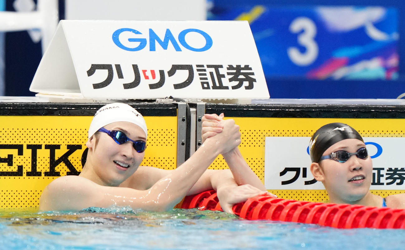 女子100メートル自由形で優勝し白井（右）と握手を交わす池江（撮影・横山健太）