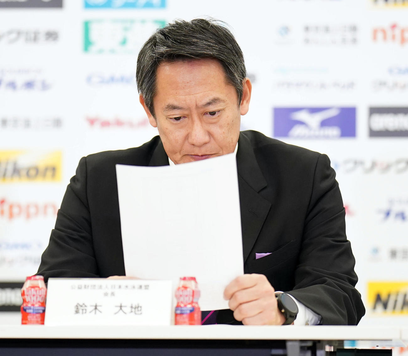 世界水泳の日本代表発表会見で、メンバー表をじっくりと見る鈴木会長（撮影・狩俣裕三）