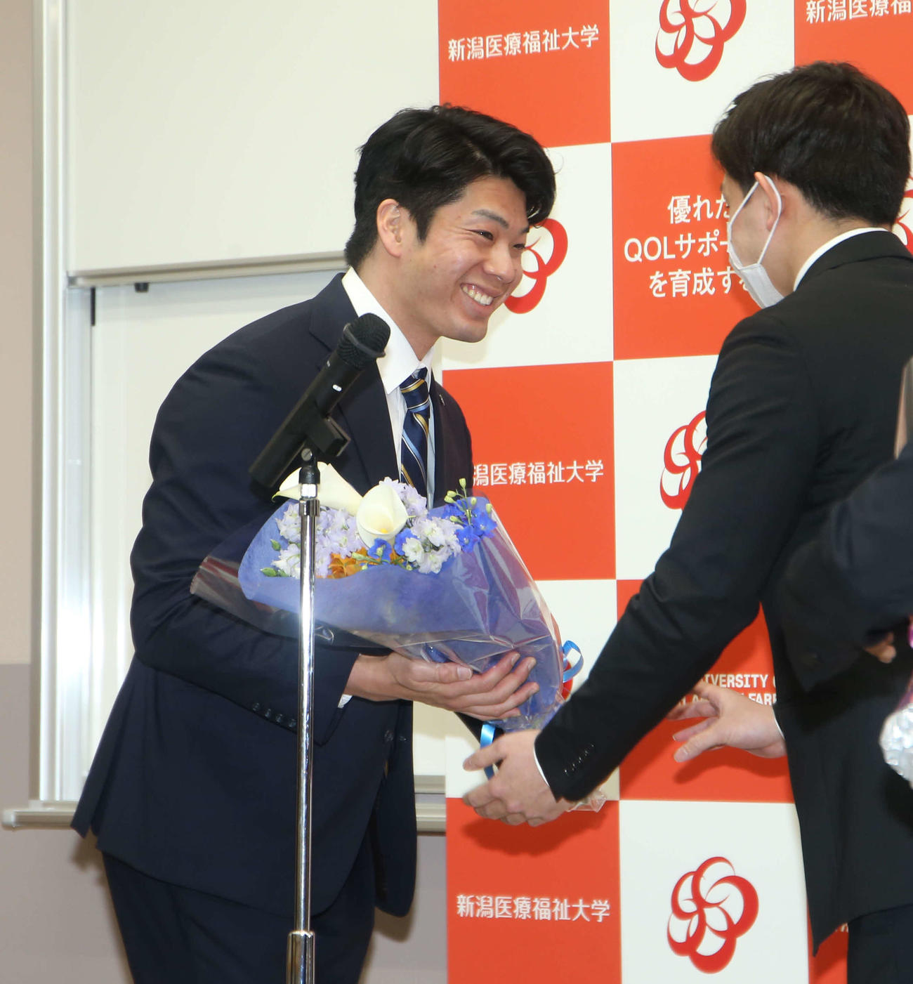 水泳部員から笑顔で花束をもらう水沼