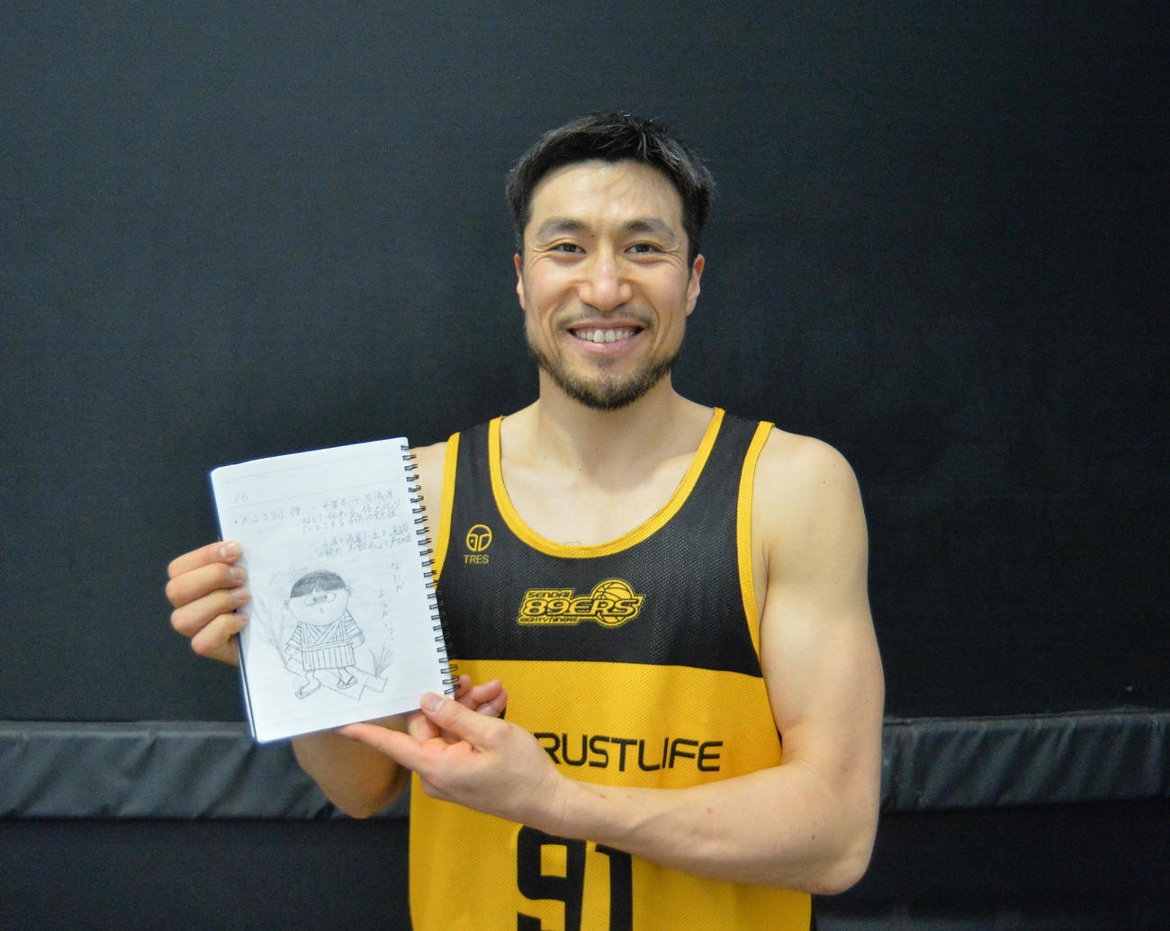 自ら描いたお気に入り妖怪「かぶきり小僧」のイラストを掲げ、笑顔を見せる片岡（撮影・濱本神威）