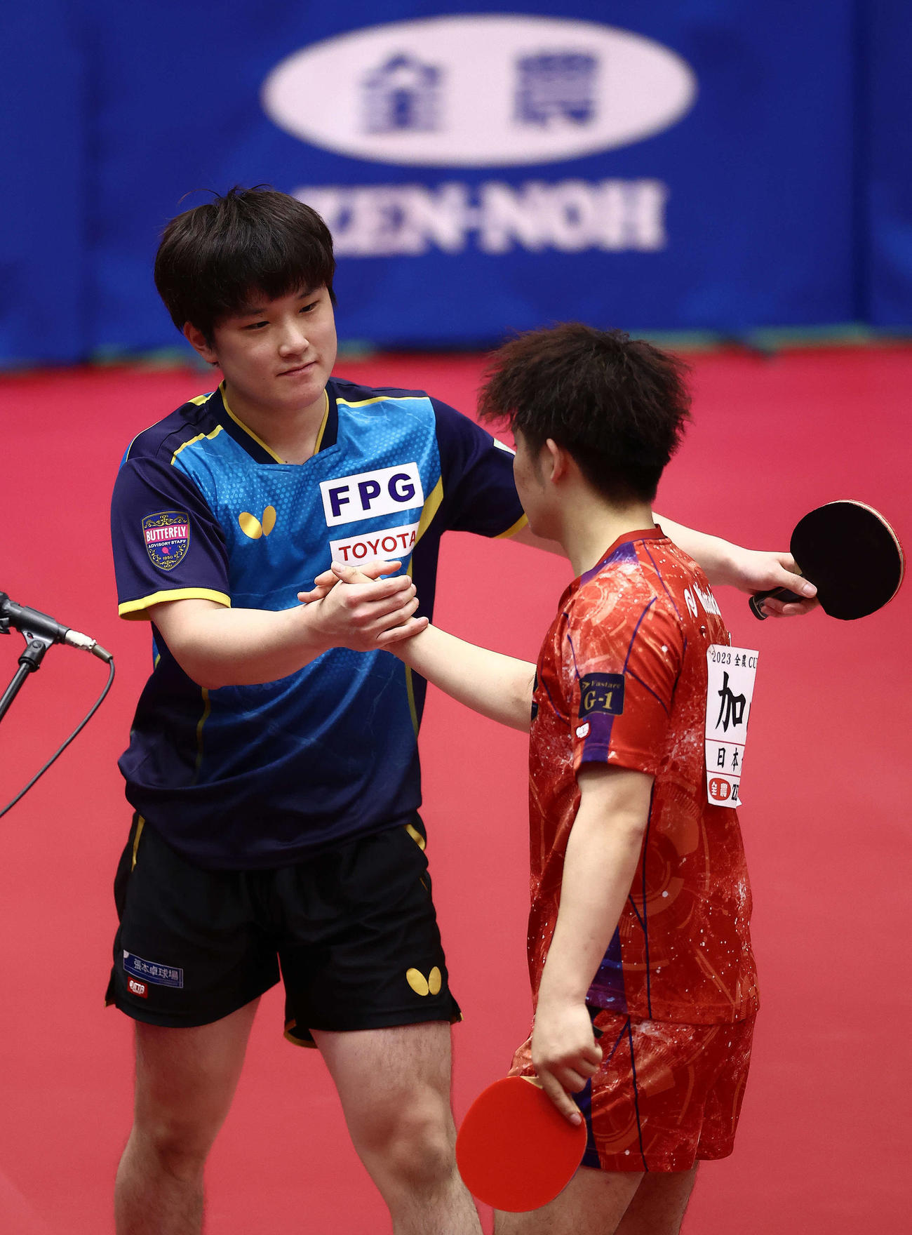 男子1回戦、加山（右）に勝利し握手を交わす張本（撮影・河田真司）