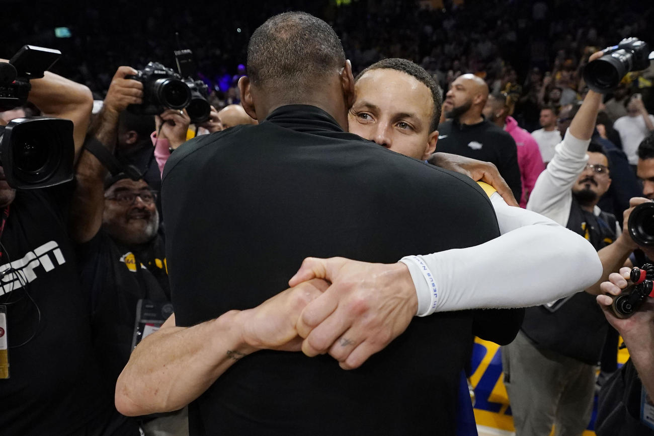 試合後に抱き合って健闘をたたえ合うレイカーズのレブロン・ジェームズとウォリアーズ・カリー（AP)