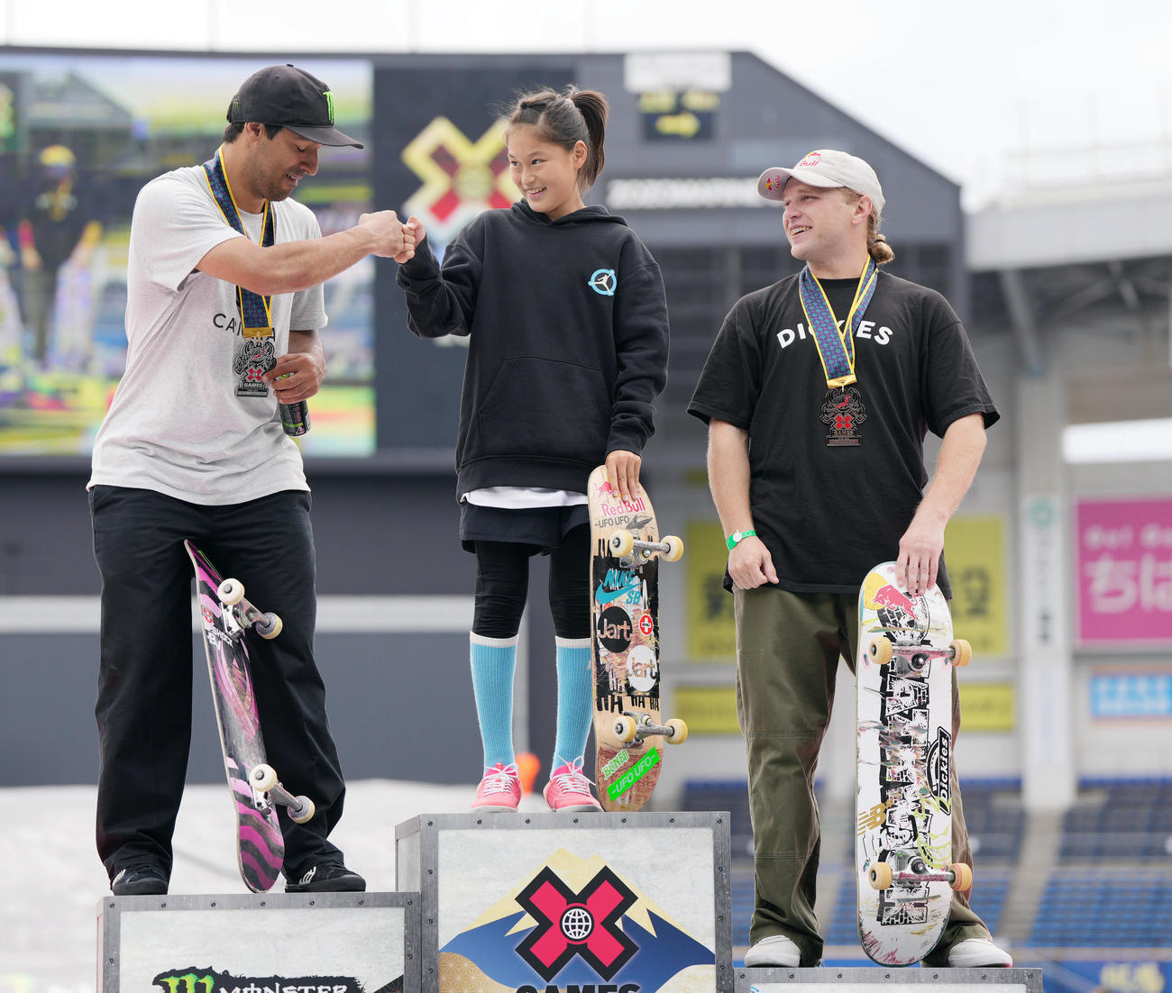 男子スケートボードストリートで優勝し、2位ホフラー（左）とタッチを交わす小野寺（中央）。右は3位フォイ（撮影・狩俣裕三）