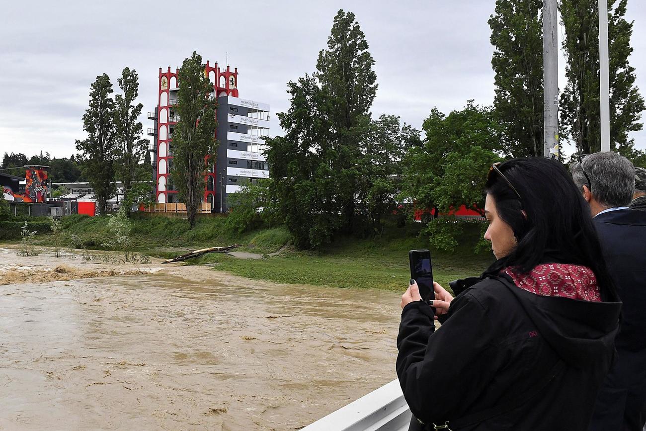 大雨で水位が上昇するサンテルノ川の画像を記録する女性（ロイター）