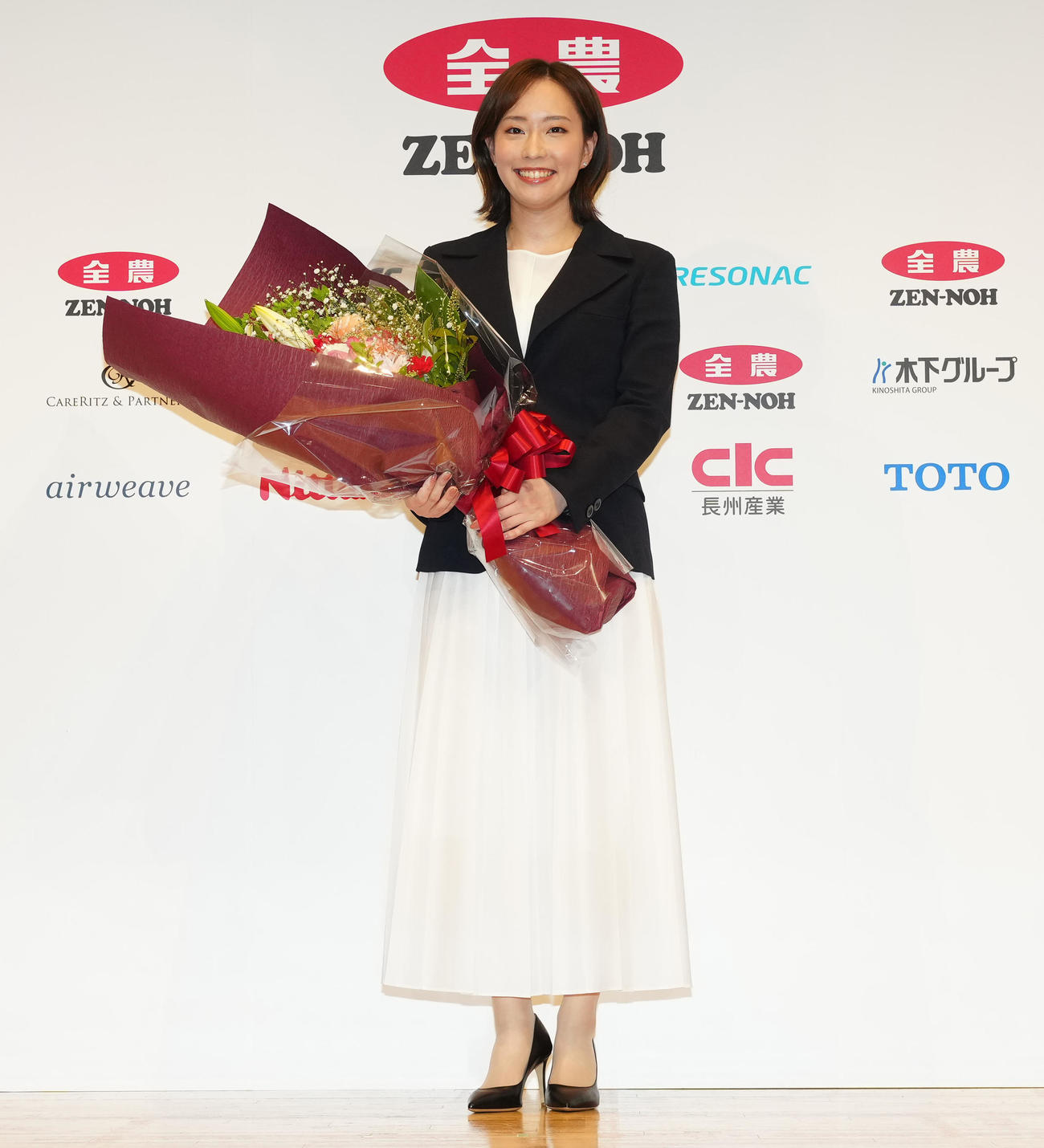 引退会見後、花束を手に写真に納まる石川さん（撮影・江口和貴）