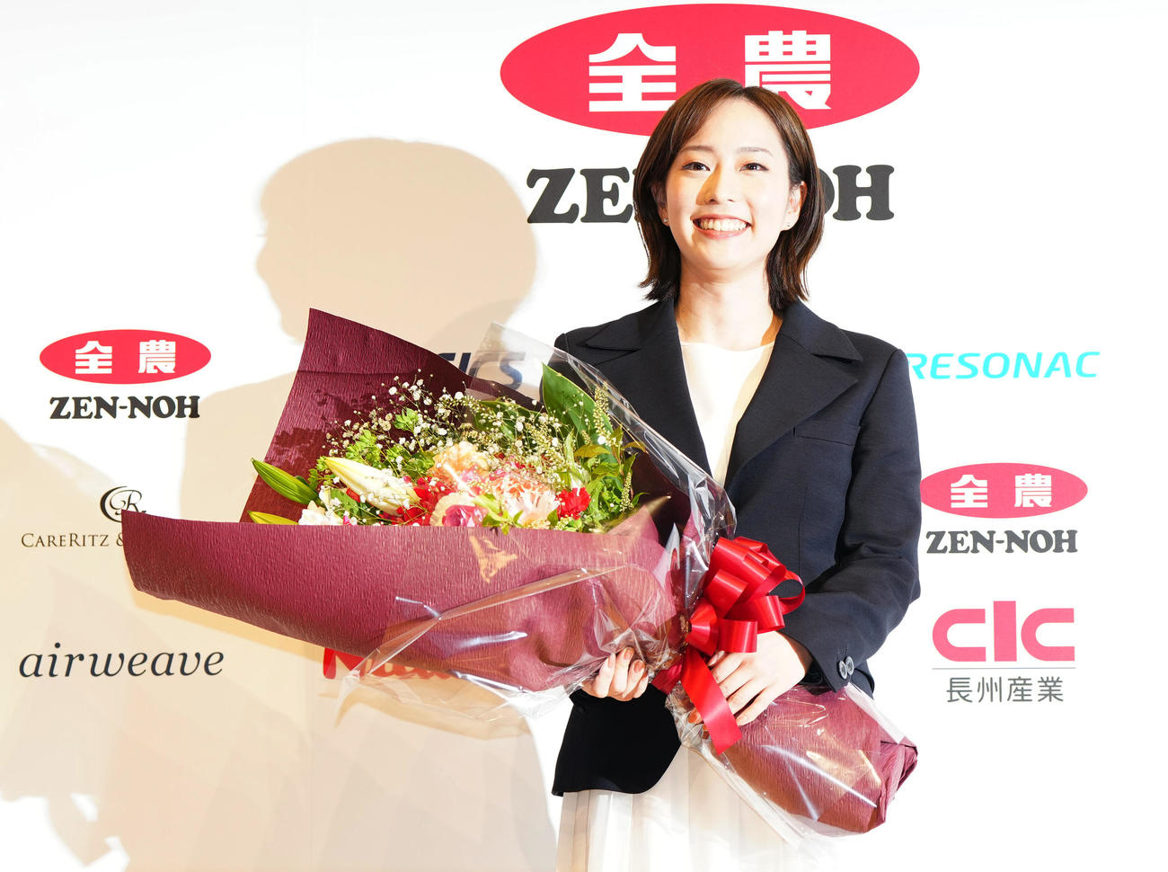 引退会見後、花束を手に写真に納まる石川さん（撮影・江口和貴）