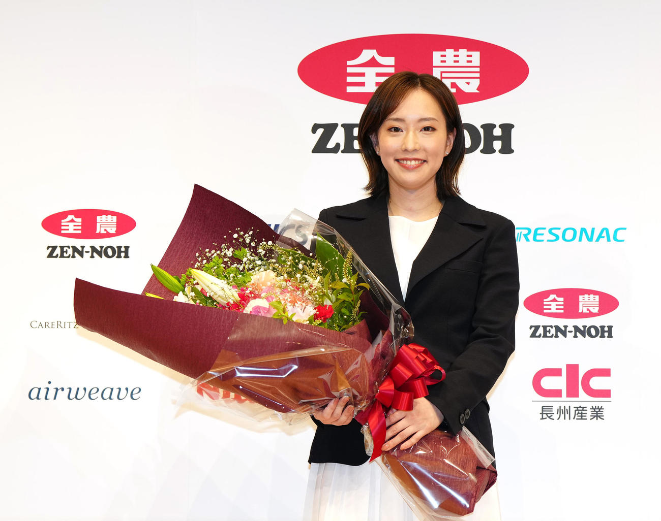 引退会見後、花束を手に写真に納まる石川さん（撮影・江口和貴）