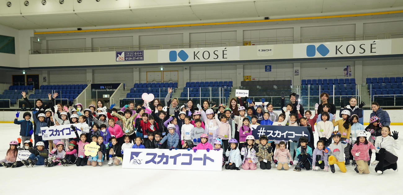 スケート教室で子どもたちといっしょに記念撮影をする高橋さん（後方中央）、村元さん（撮影・狩俣裕三）