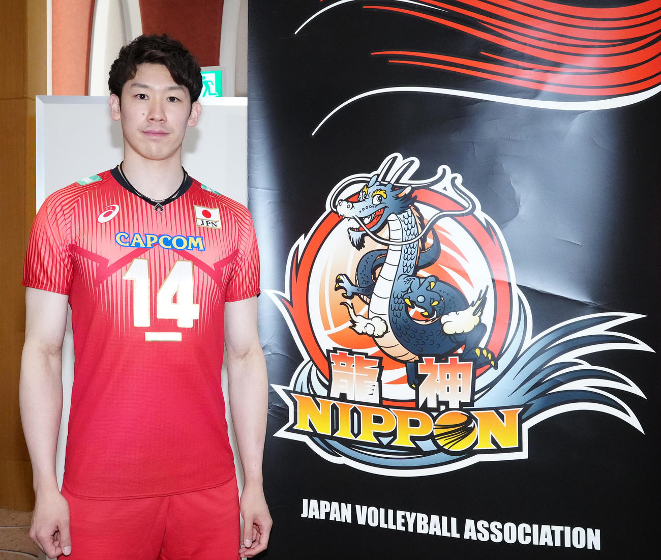 龍神NIPPONのロゴの横で写真に納まるバレーボール男子日本代表の石川（撮影・江口和貴）