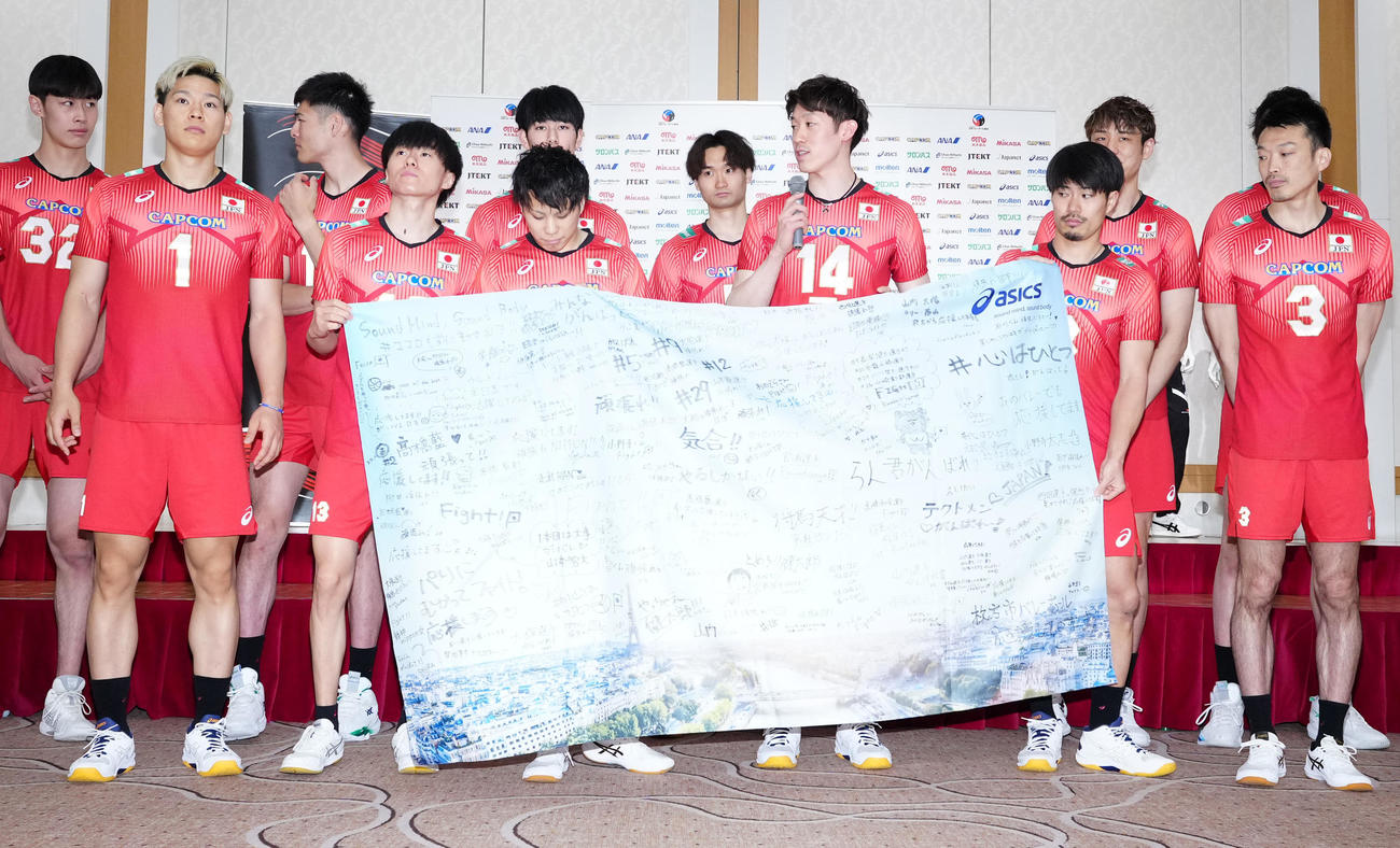 ファンからのメッセージが書かれた旗を手にコメントする石川（左から8人目）（撮影・江口和貴）