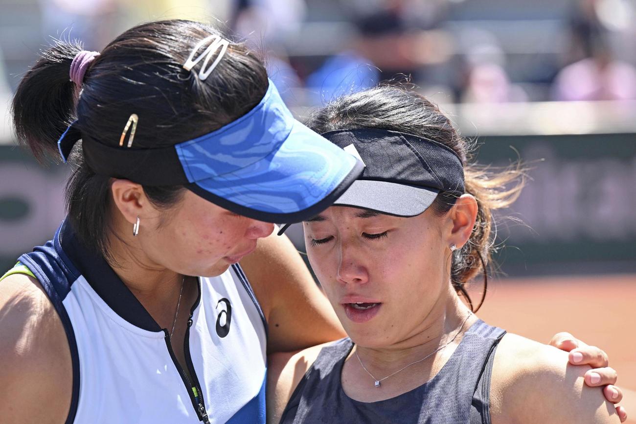 4日、女子ダブルス3回戦で失格となり、涙ぐむ加藤未唯（右）をなぐさめるアルディラ・スーチャディ（共同）
