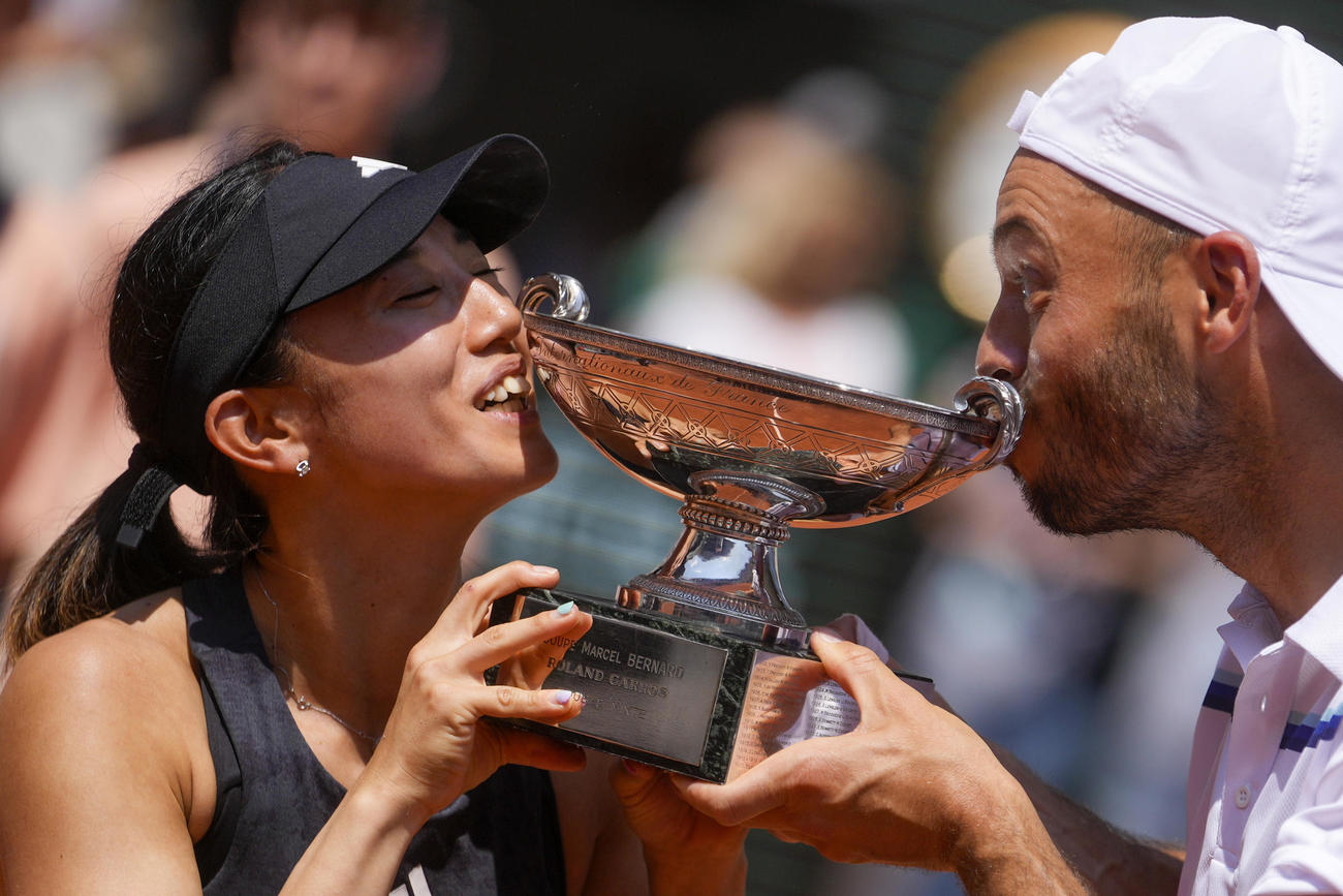 テニスの全仏オープン混合ダブルスで優勝し、トロフィーにキスする加藤未唯（左）、ティム・プッツ組（AP）