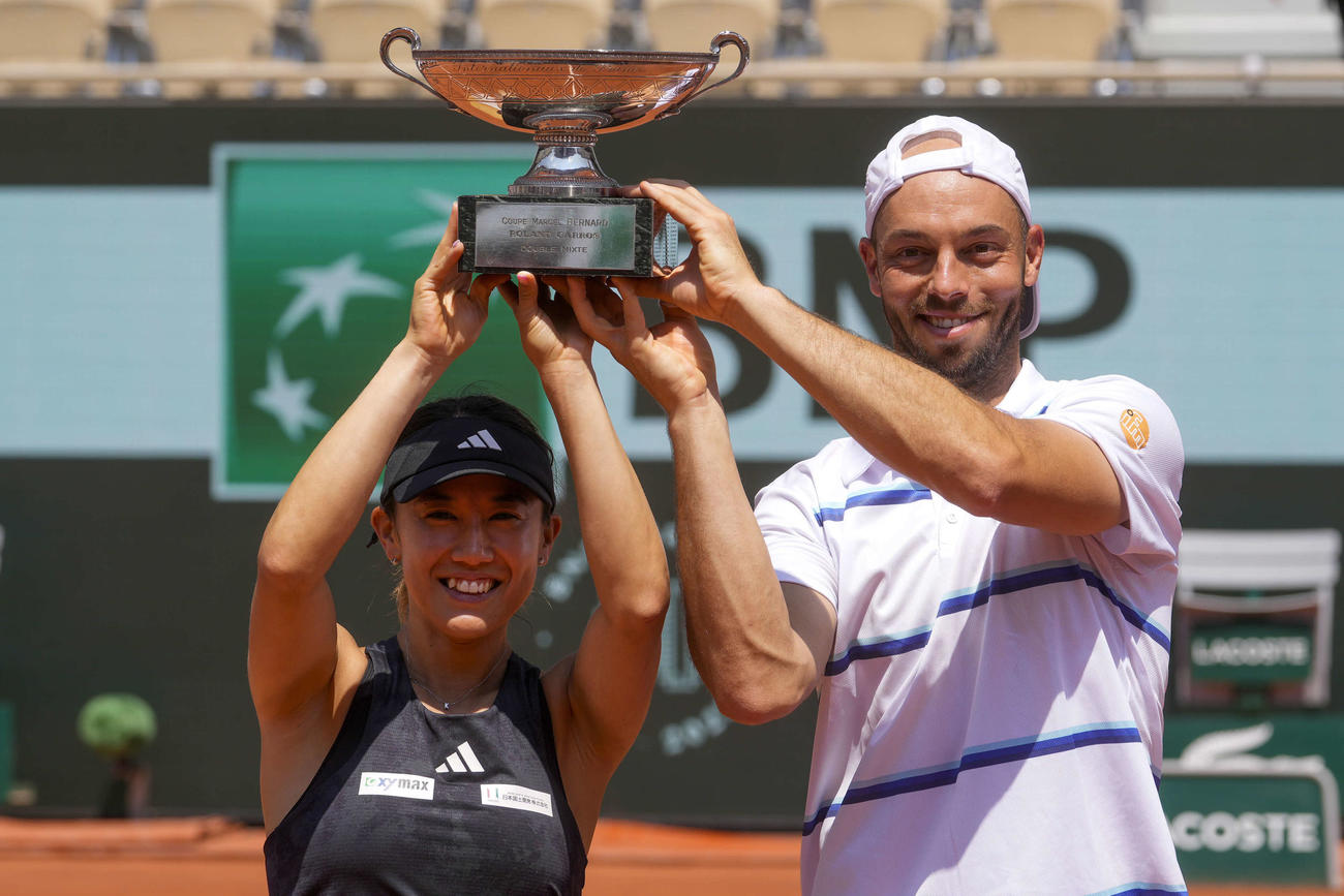 テニスの全仏オープン混合ダブルスで優勝し、トロフィーを掲げて笑顔の加藤未唯（左）、ティム・プッツ組（AP）