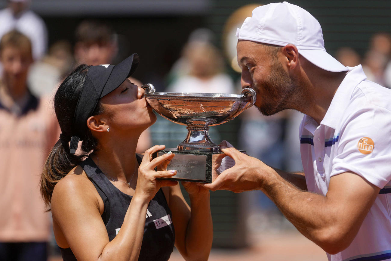 テニスの全仏オープン混合ダブルスで優勝し、トロフィーにキスする加藤未唯（左）、ティム・プッツ組（AP）