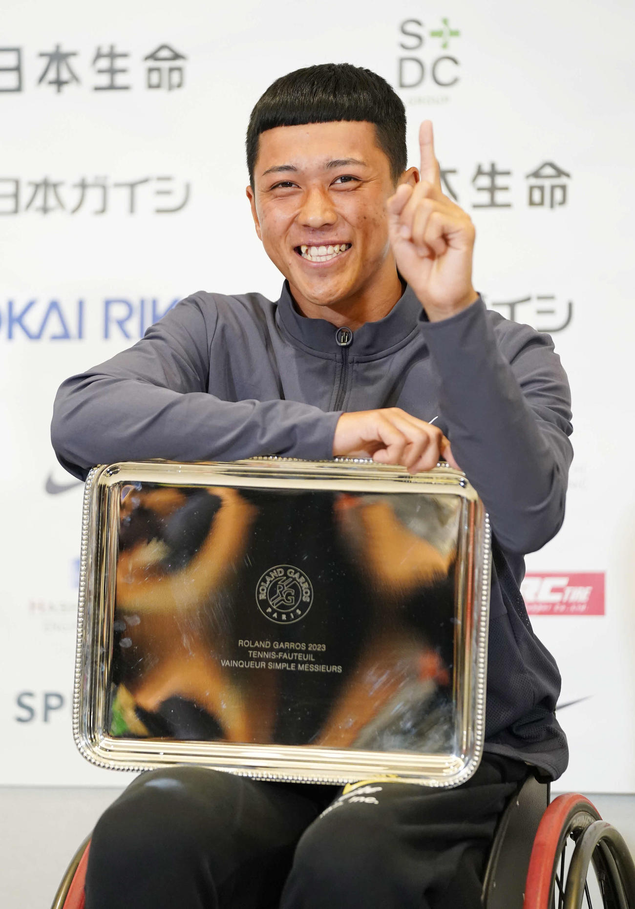 車いす全仏オープンで優勝し帰国会見でプレートを手に1番ポーズを披露するプロテニスプレーヤーの小田（撮影・小沢裕）