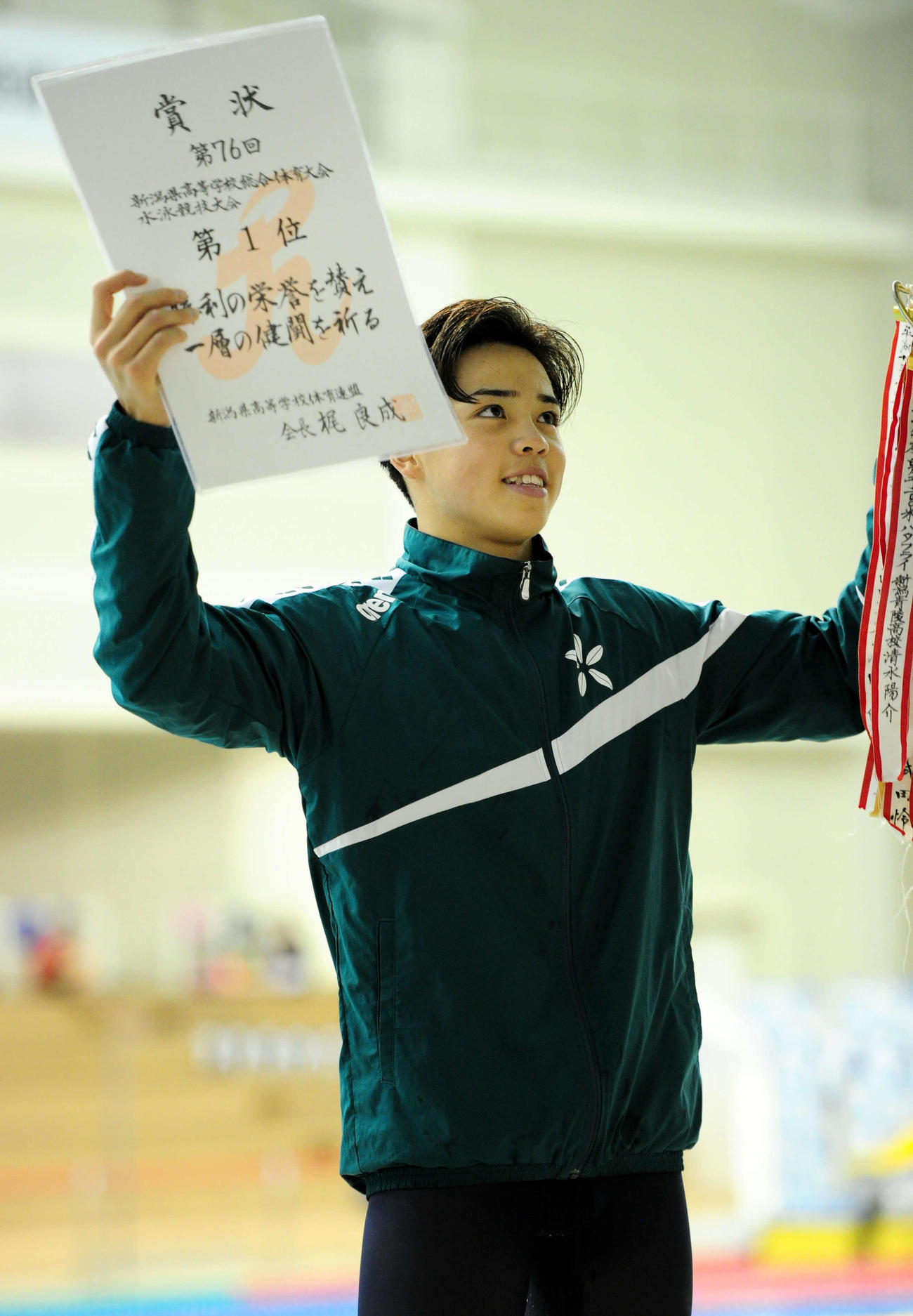 男子100メートルバタフライで大会新Vを決め、表彰台で笑顔の長岡大手・峠
