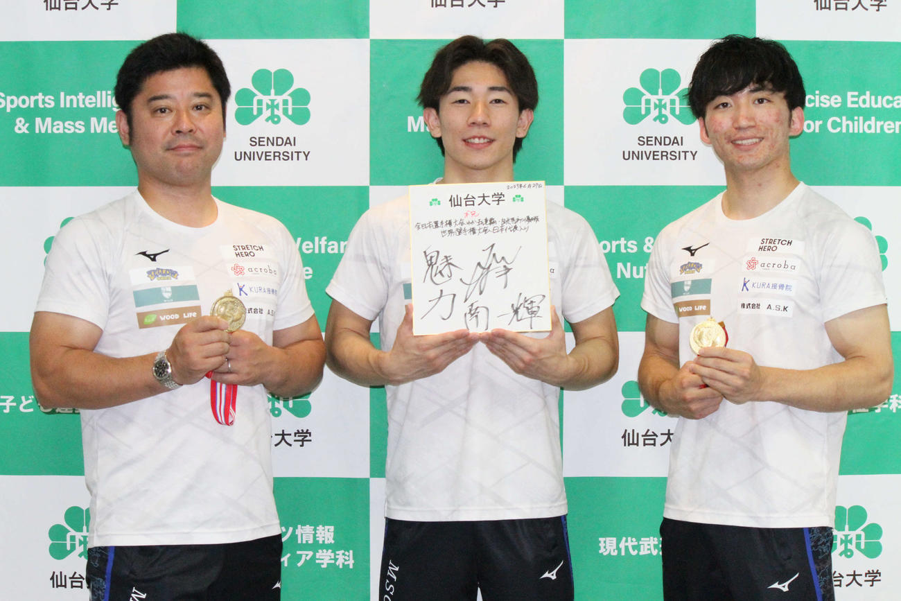メダルと色紙を手に記念撮影する、左からエムズスポーツクラブ松村社長、南一輝、村上コーチ