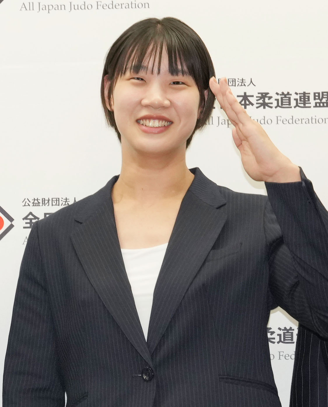 パリ五輪代表の内定会見で敬礼しながら記念撮影をする女子70キロ級の新添（撮影・狩俣裕三）