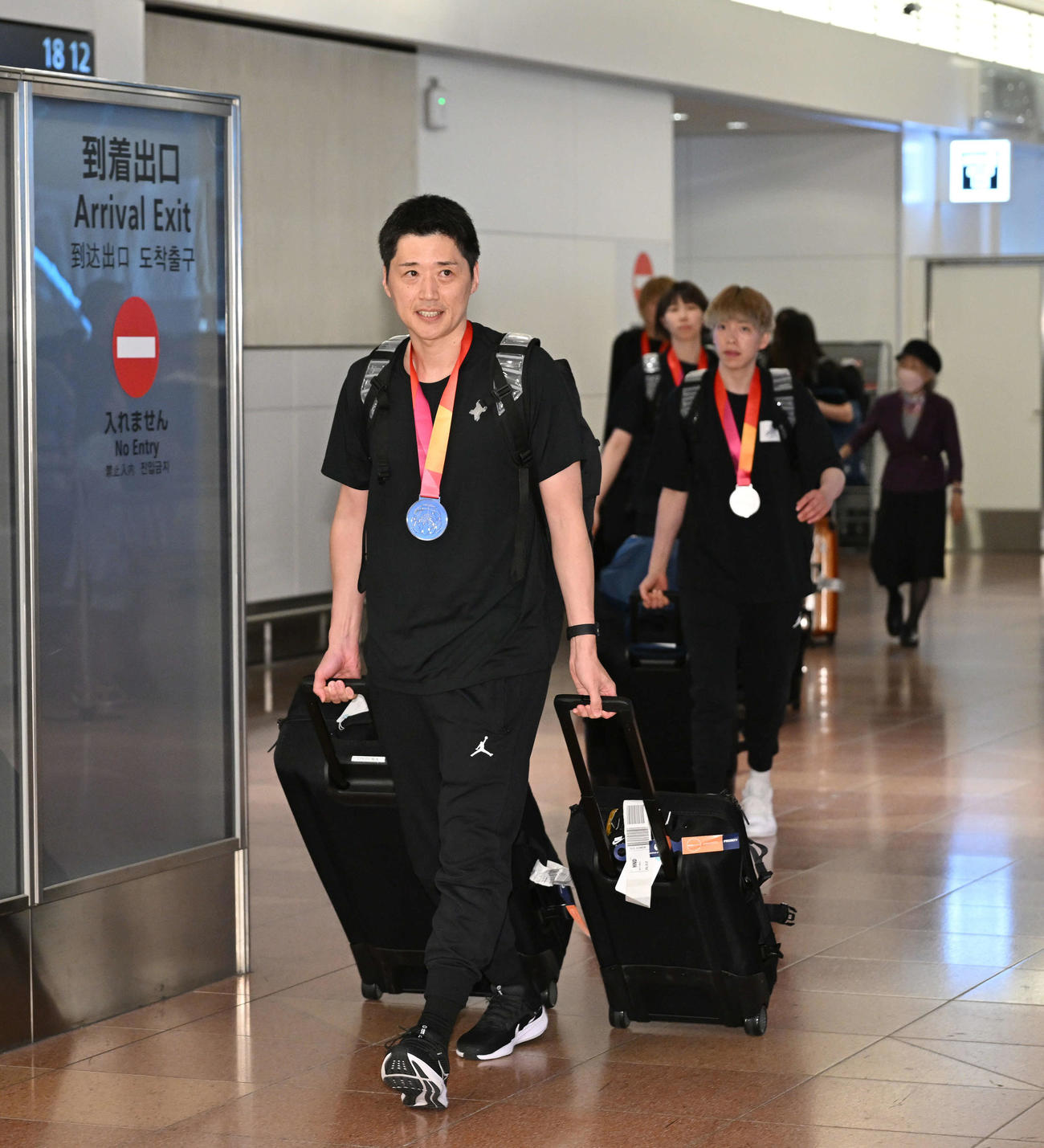 銀メダルを胸に帰国した恩塚監督（手前）らバスケットボール女子日本代表（撮影・滝沢徹郎）