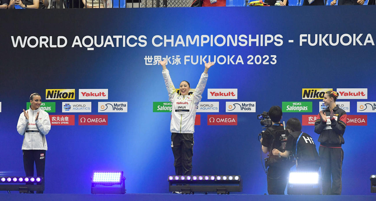 世界水泳2023福岡大会第2日　アーティスティックスイミング女子ソロテクニカルの表彰式で、金メダルの乾友紀子（中央）は笑顔で手を振る（撮影・岩下翔太）