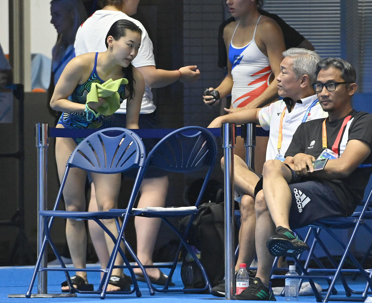 女子3メートル飛板飛び込み予選、5本目の演技を終え、安田千万樹コーチ（右から2人目）と話す三上紗也可（撮影・岩下翔太）