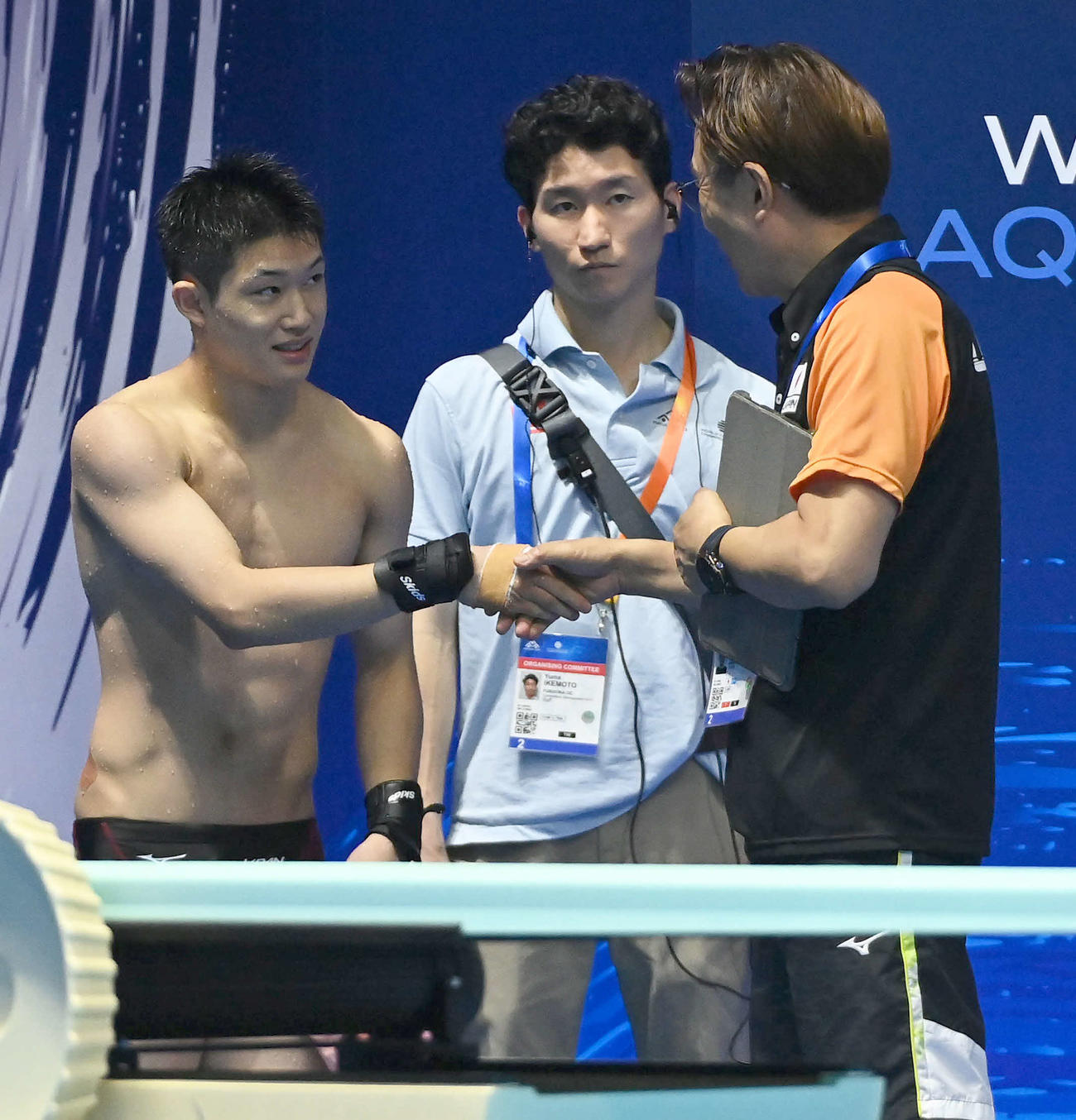 世界水泳2023福岡大会第8日　男子高飛び込み予選、6本目の演技を終えて馬淵崇英コーチ（右）と握手を交わす玉井陸斗（撮影・岩下翔太）