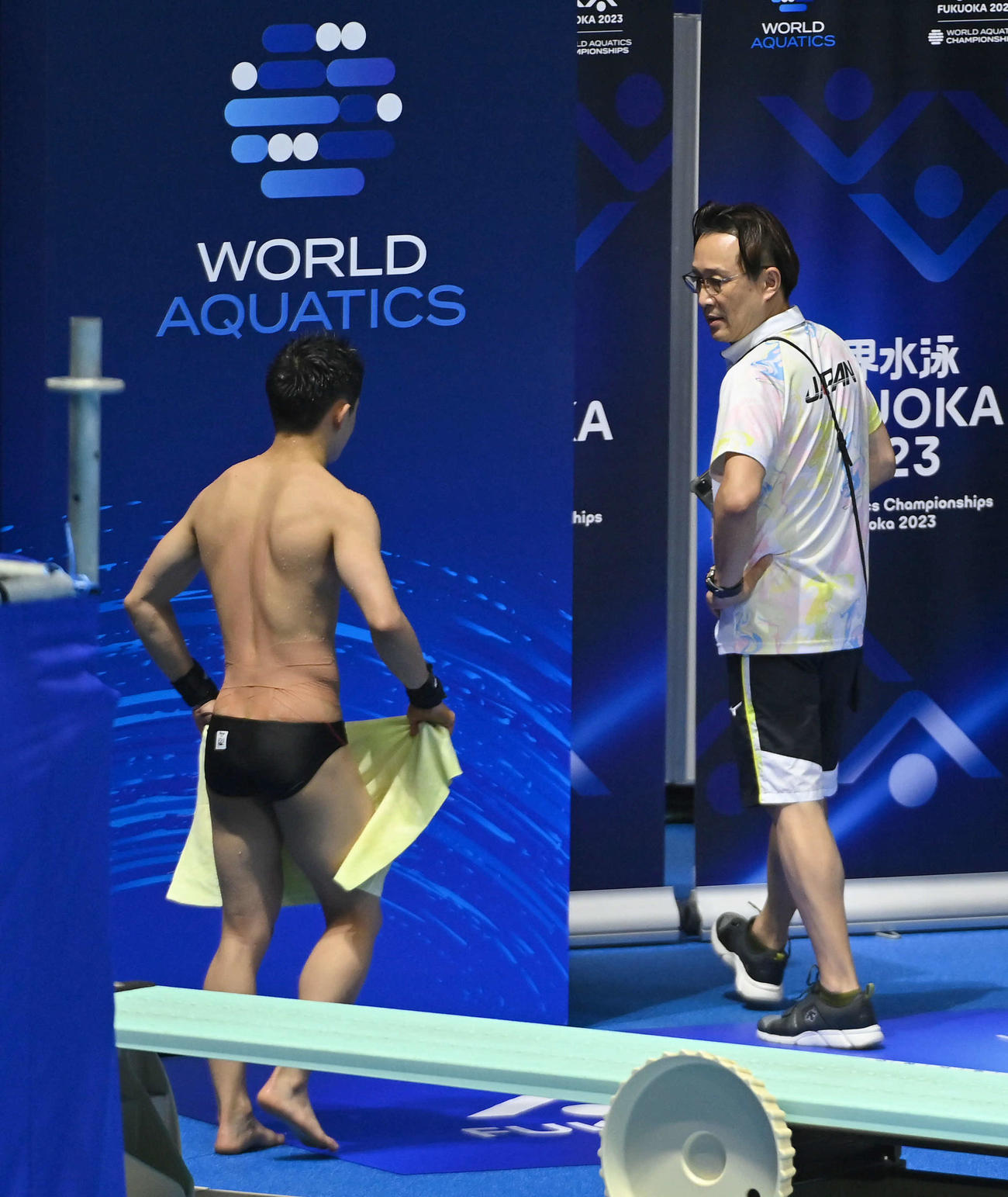 世界水泳2023福岡大会第9日　男子高飛び込み決勝、1本目の演技を終えた玉井陸斗（左）と舞台裏へ向かう馬淵崇英コーチ（撮影・岩下翔太）