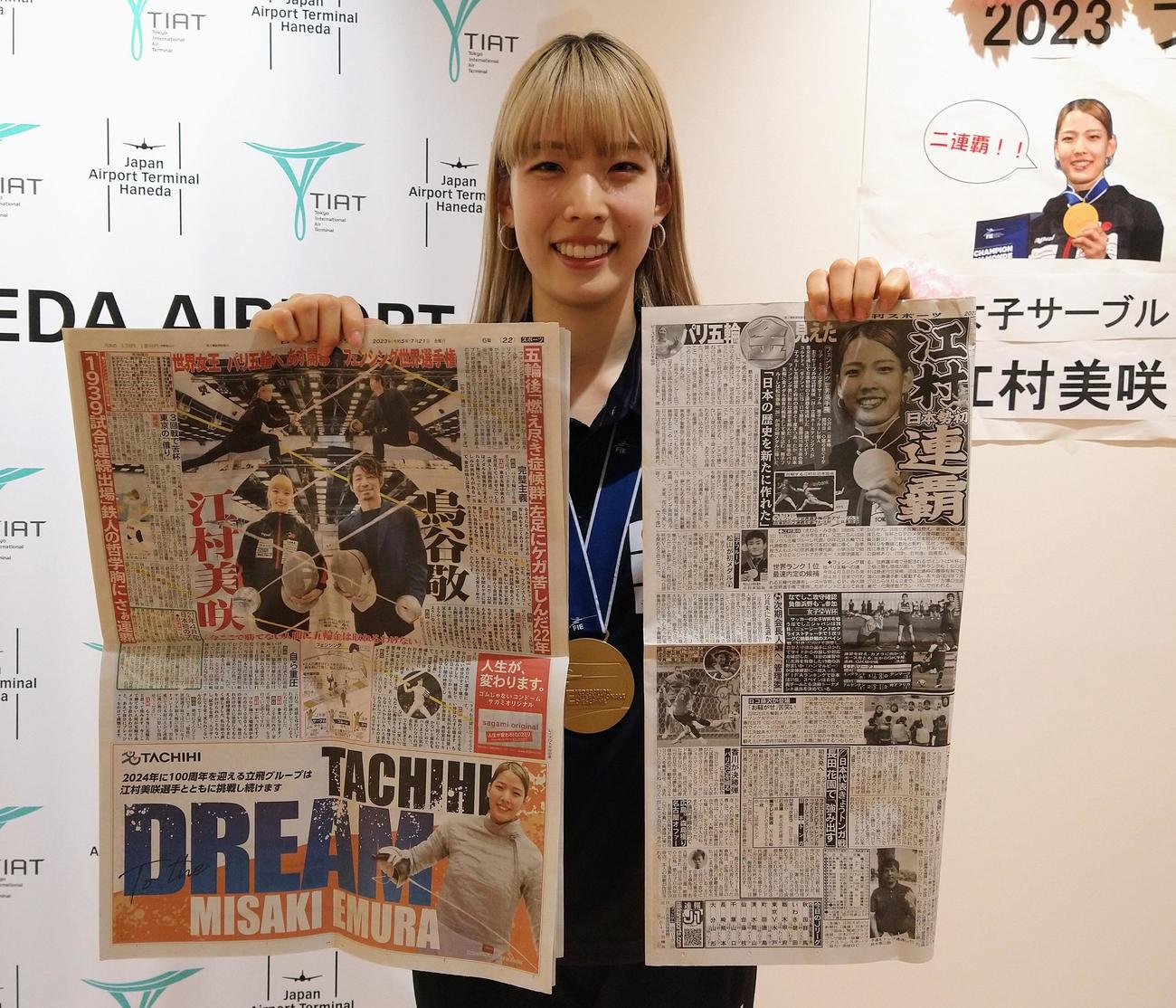 女子サーブル個人で日本勢初の2連覇を遂げたフェンシング世界選手権から帰国し、開幕前の企画紙面と大会中の快挙を伝える本紙を手に笑顔の江村（撮影・木下淳）