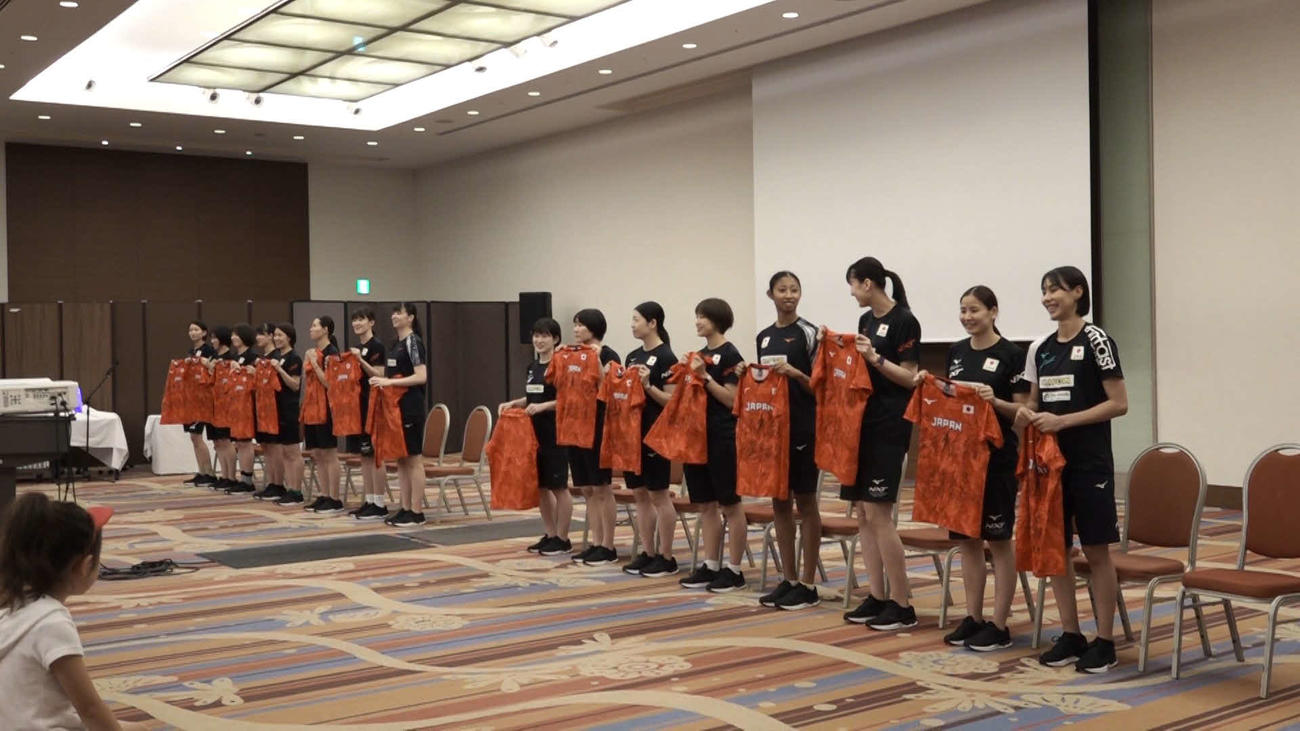 交流イベントでサイン入りユニフォームを広げるバレーボール女子日本代表