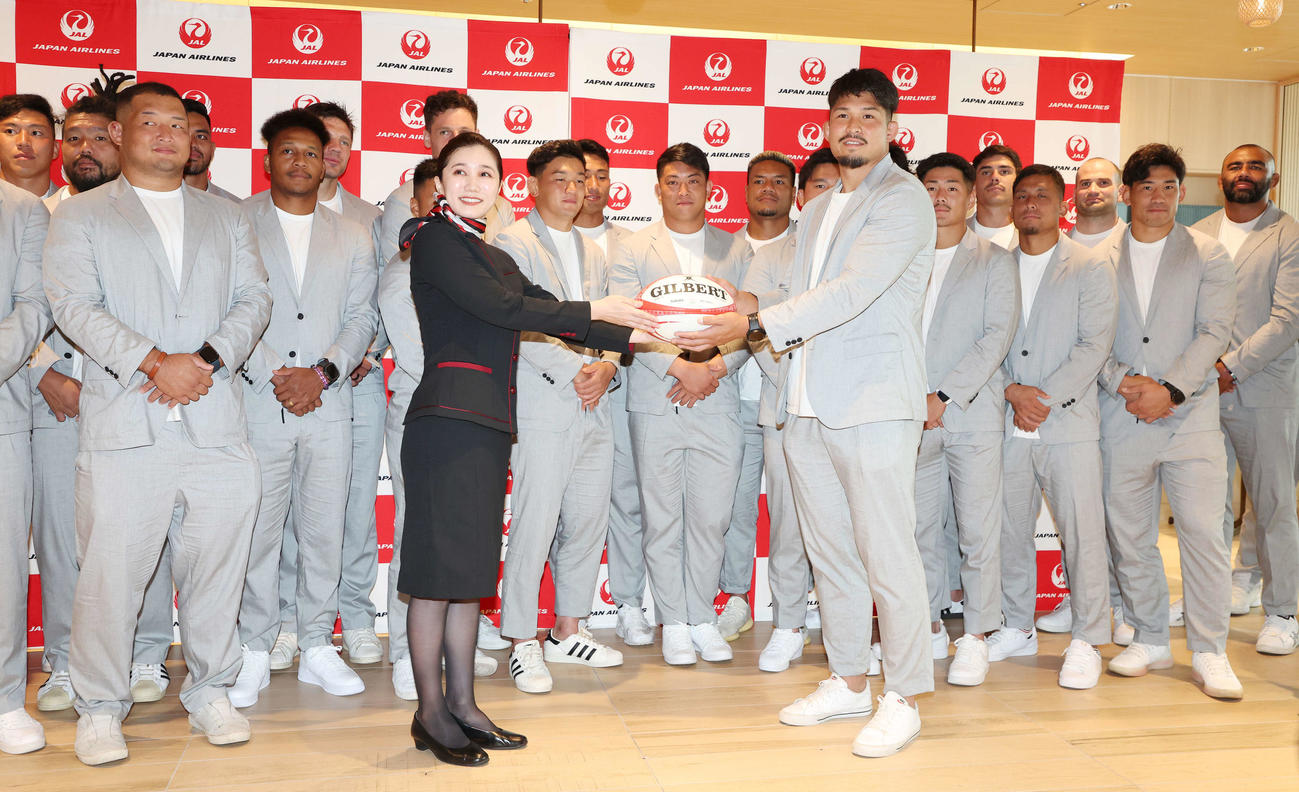 ラグビー日本代表出発式でラグビーボールをJAL職員に渡す姫野主将（手前右）（撮影・宮地輝）