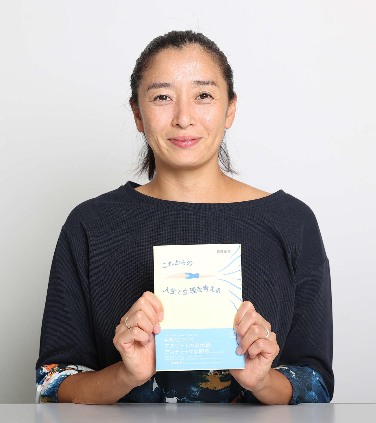 著書「これからの人生と生理を考える」を手にする競泳元日本代表の伊藤さん（撮影・河野匠）