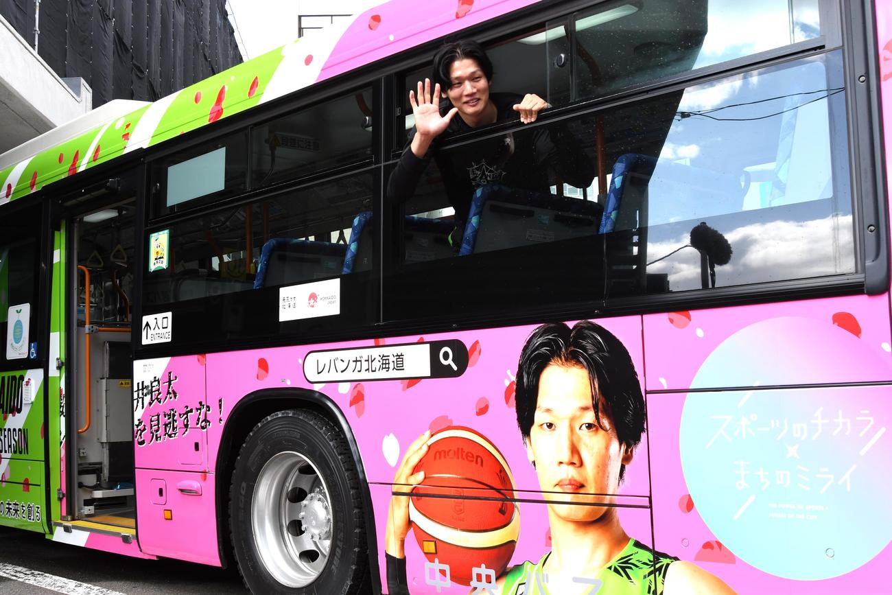 ラッピングバスの窓から手を振るレバンガ北海道の桜井（撮影・石井翔太）