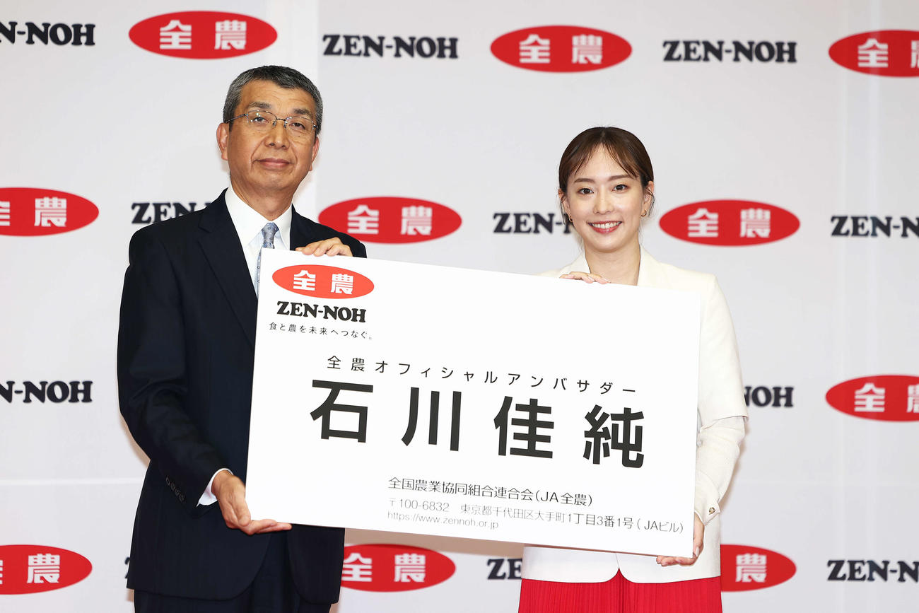 全農オフィシャルアンバサダーに就任し、野口理事長（左）から巨大名刺を受け取る石川佳純さん（撮影・河田真司）