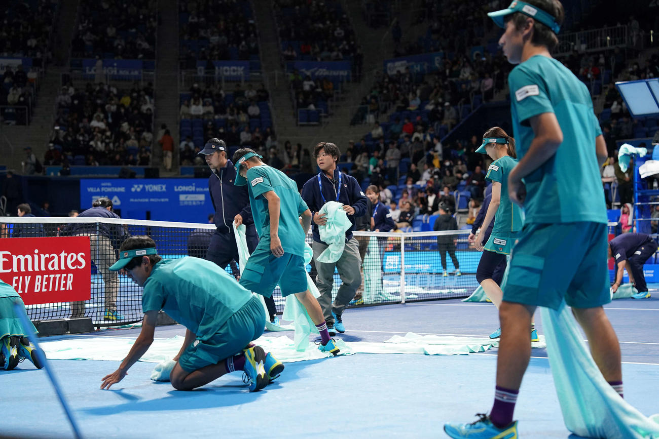 男子シングルス準決勝　望月対カラツェフの試合で、天井が閉まった後、雨で濡れたコートを拭くスタッフ（撮影・鈴木みどり）