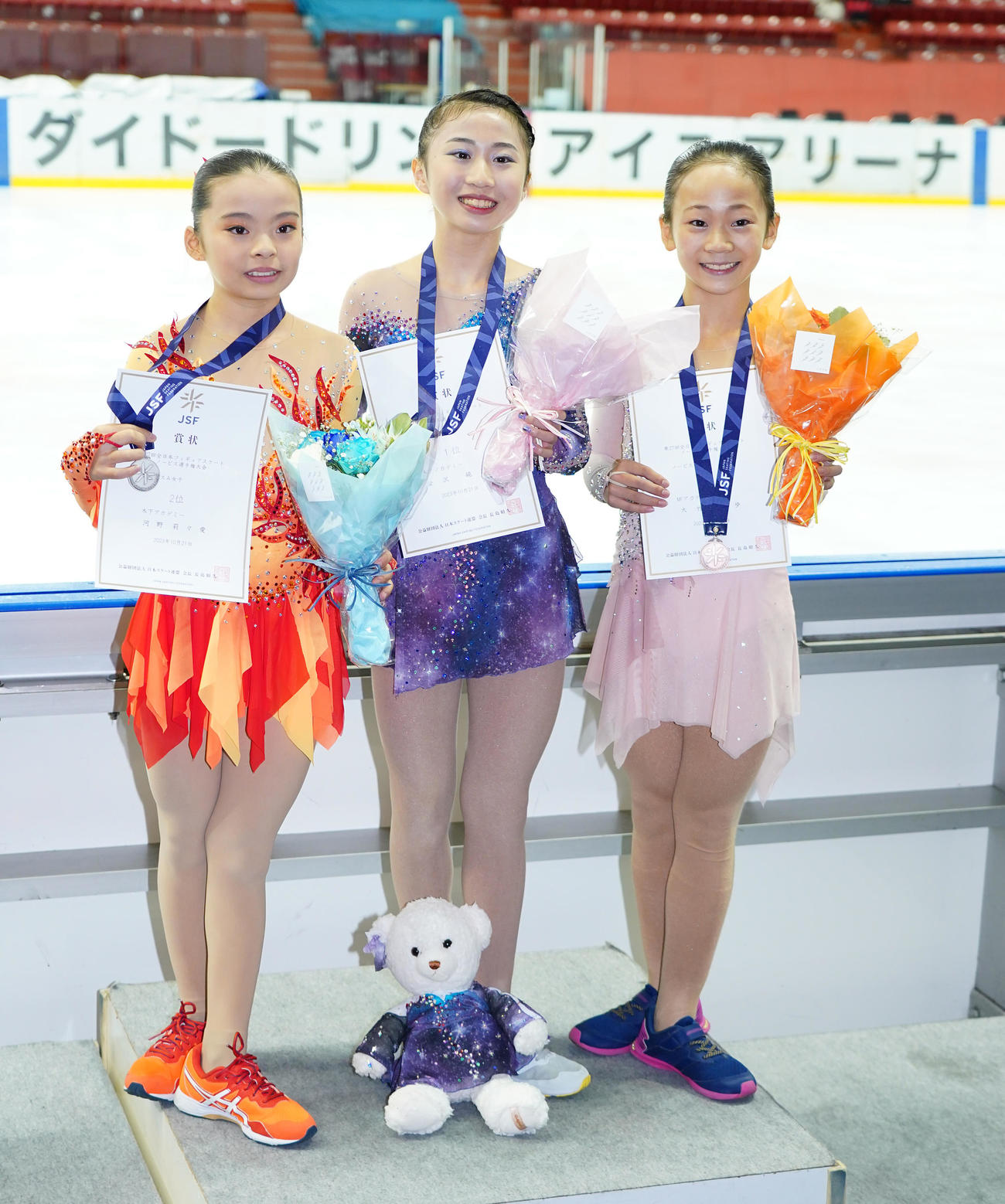 女子ノービスAで優勝し、記念写真に納まる金沢（中央）。左は2位の河野、右は3位の大竹（撮影・菅敏）
