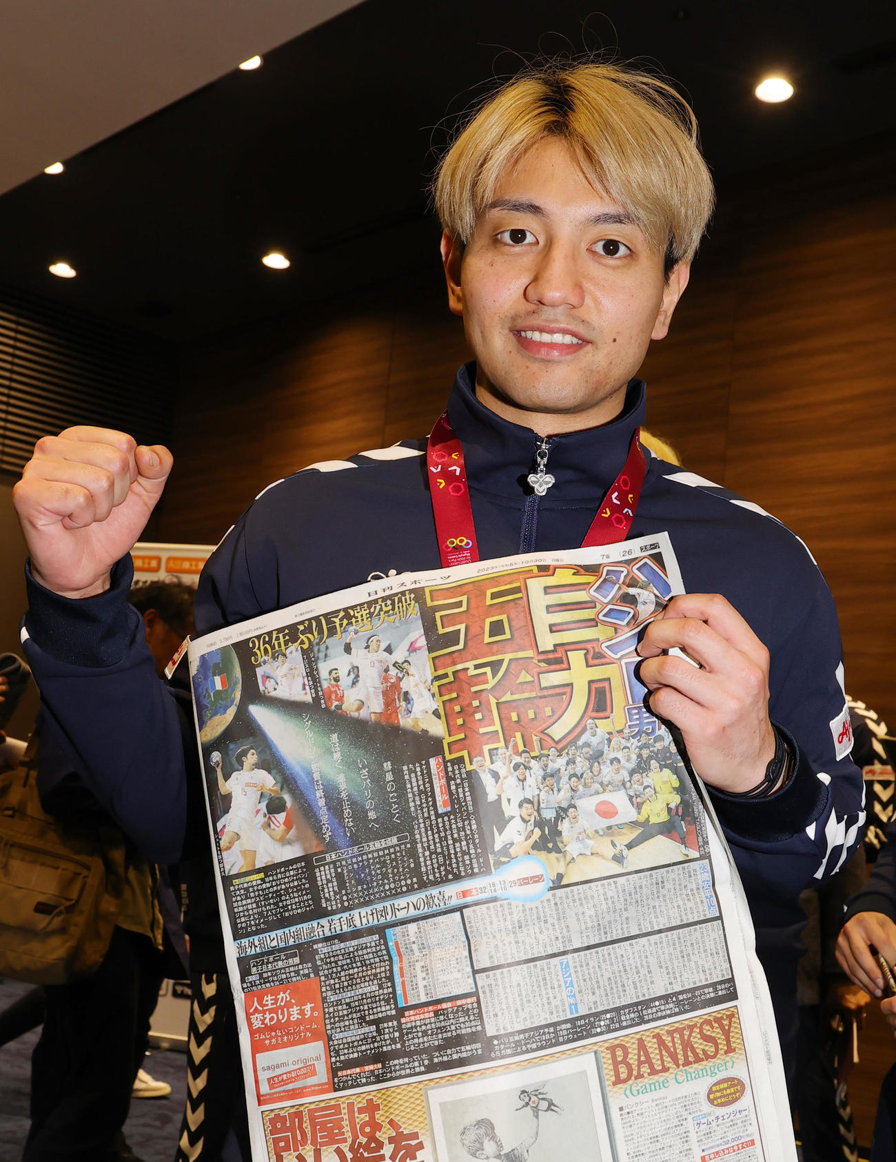 パリ五輪の出場権を獲得し、会見で快挙を報じる日刊スポーツを手にするンドボール男子日本代表の東江主将（撮影・野上伸悟）