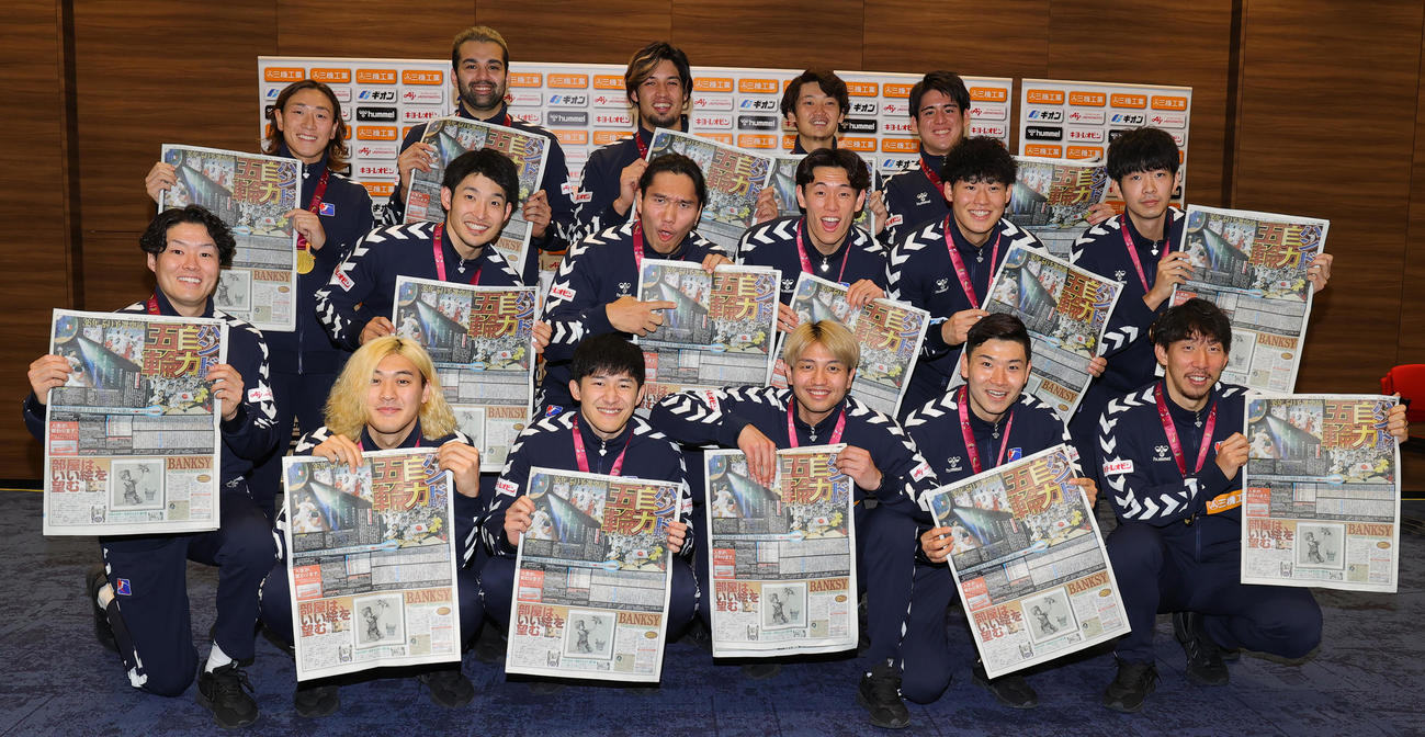 パリ五輪の出場権を獲得したハンドボール男子日本代表の選手たちは、快挙を報じる日刊スポーツを手に喜ぶ（撮影・野上伸悟）