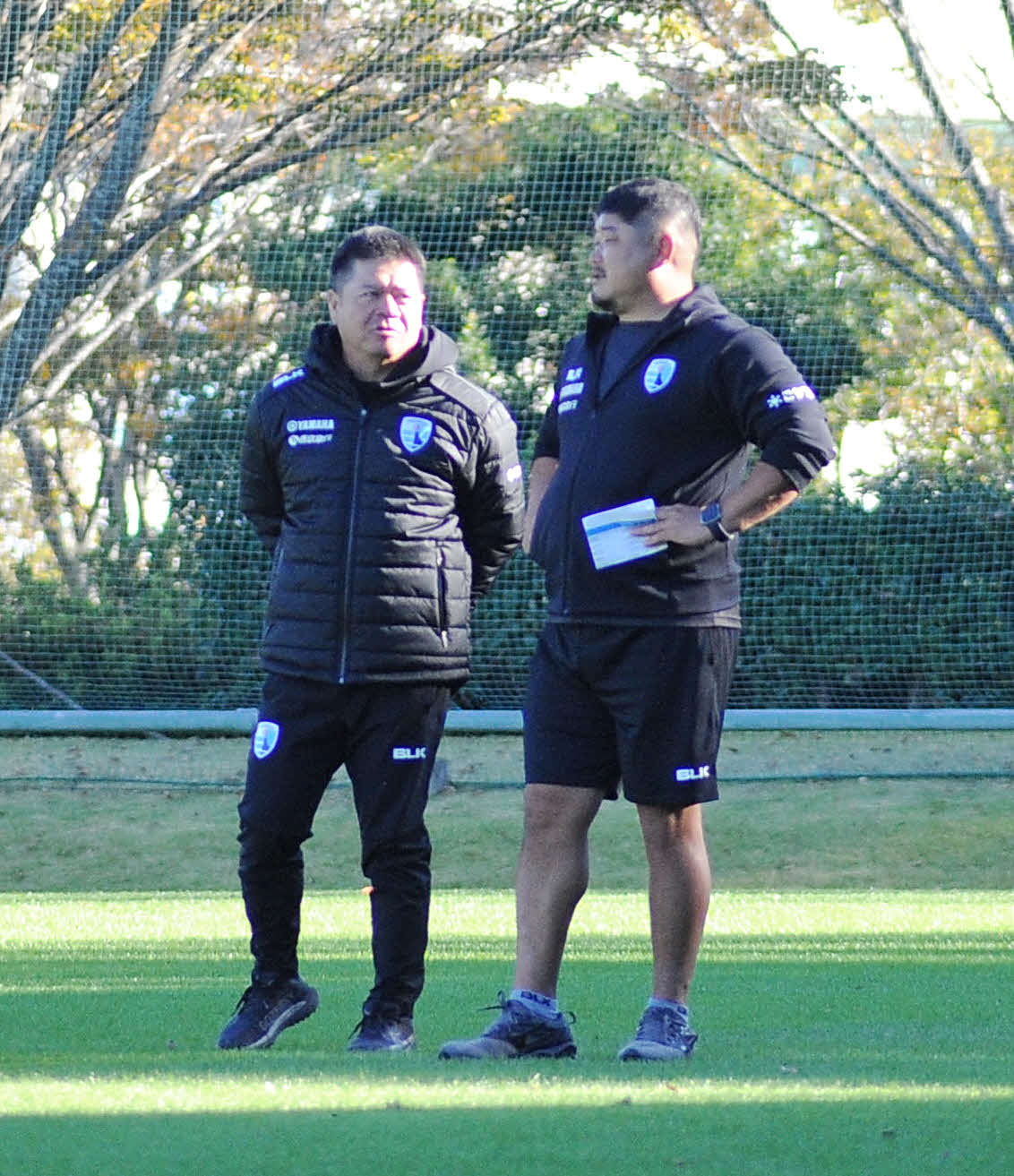 グラウンド上で会話する静岡ブルーレヴズの藤井監督（左）と長谷川アシスタントコーチ