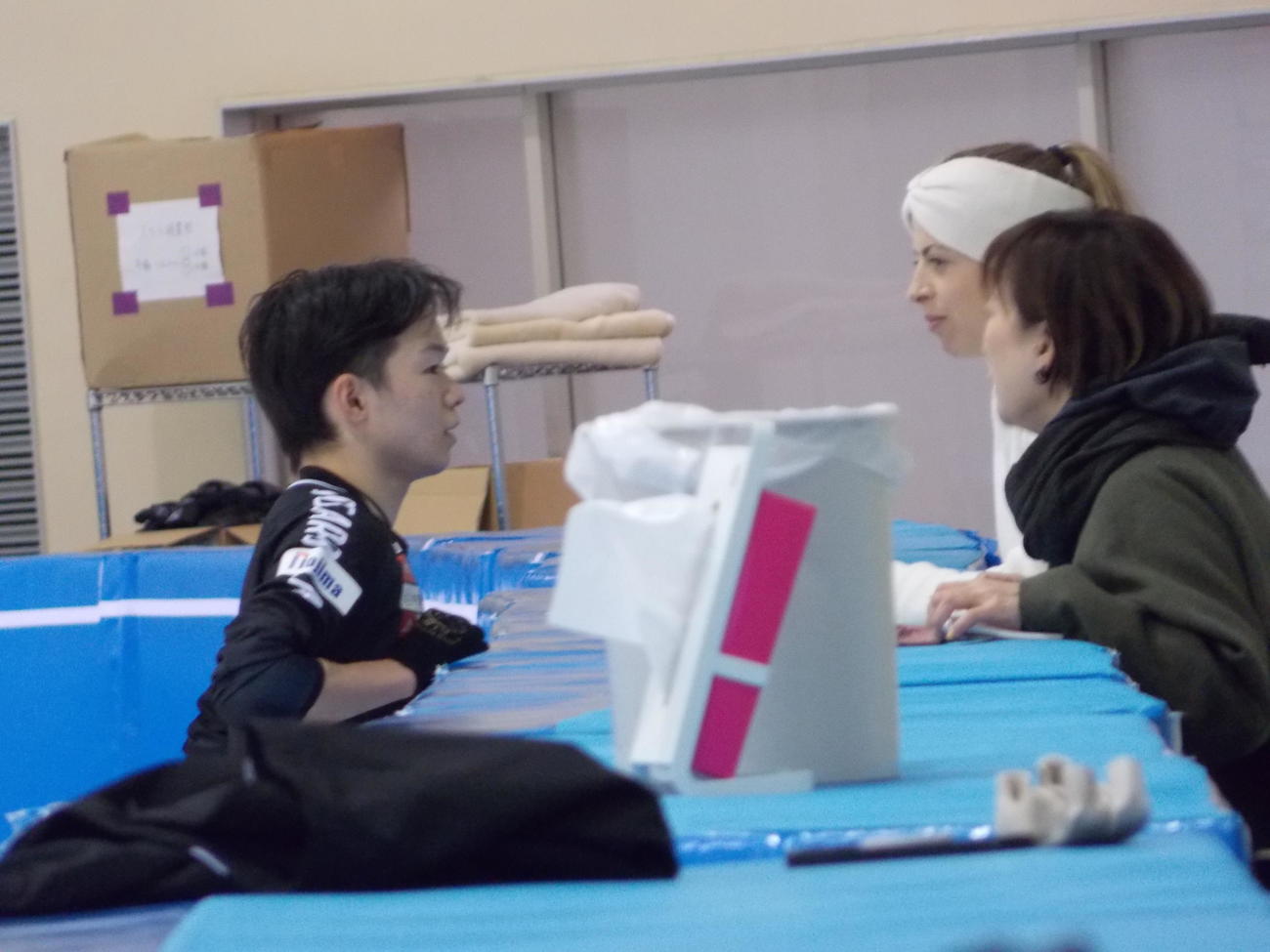 公開練習でカロリナ・コストナー・コーチ（右奥）と会話する鍵山優真（左）（撮影・松本航）