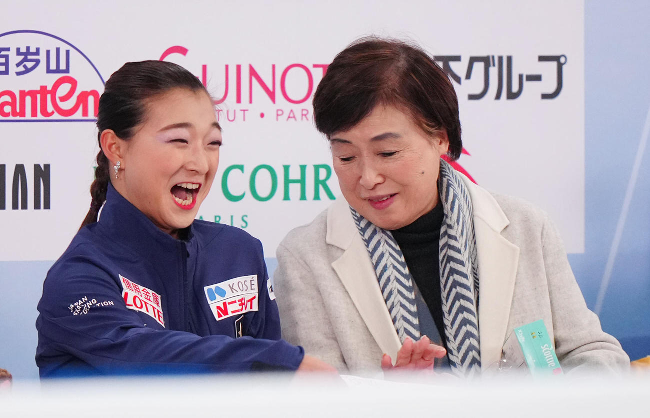 女子SPの演技後、キス・アンド・クライで笑顔を見せる坂本（左）。右は中野コーチ