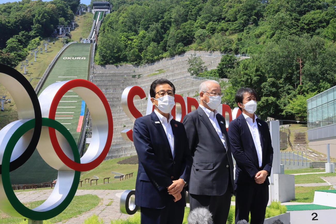 大倉山ジャンプ競技場の五輪マーク前で取材に応じる秋元克広札幌市長（左端）ら（2022年7月27日撮影）