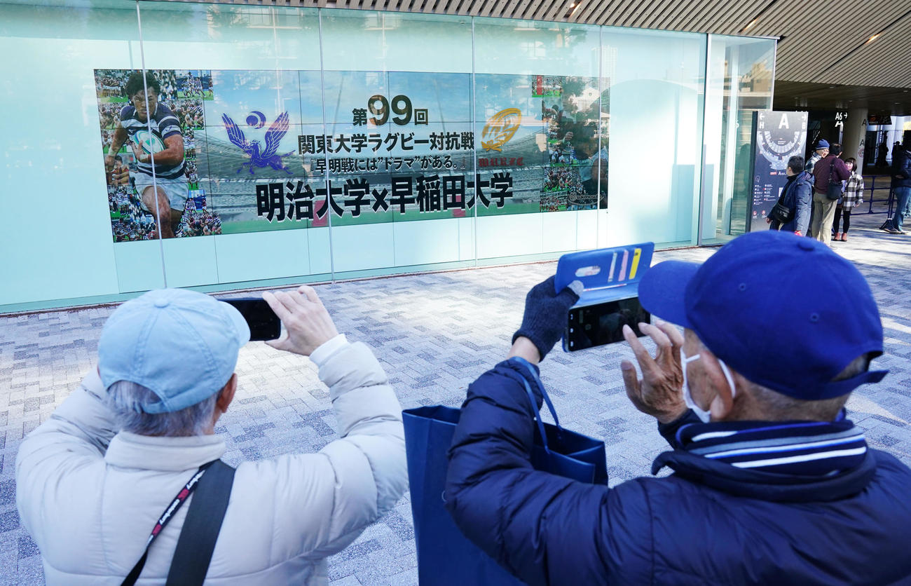 早大対明大　早明戦100周年記念の電光掲示板を撮影する観客（撮影・横山健太）